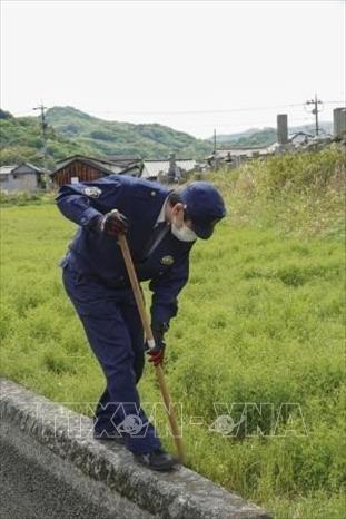Cảnh sát tìm kiếm con trăn bị xổng trong bãi cỏ xung quanh khu căn hộ ở thành phố Okayama, Nhật Bản ngày 18/4/2022. Ảnh: Kyodo/TTXVN